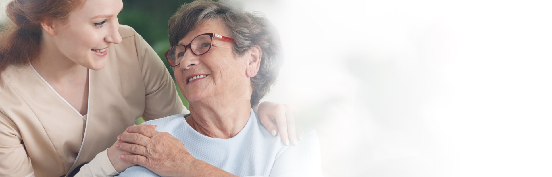 caregiver and senior woman smiling with each other