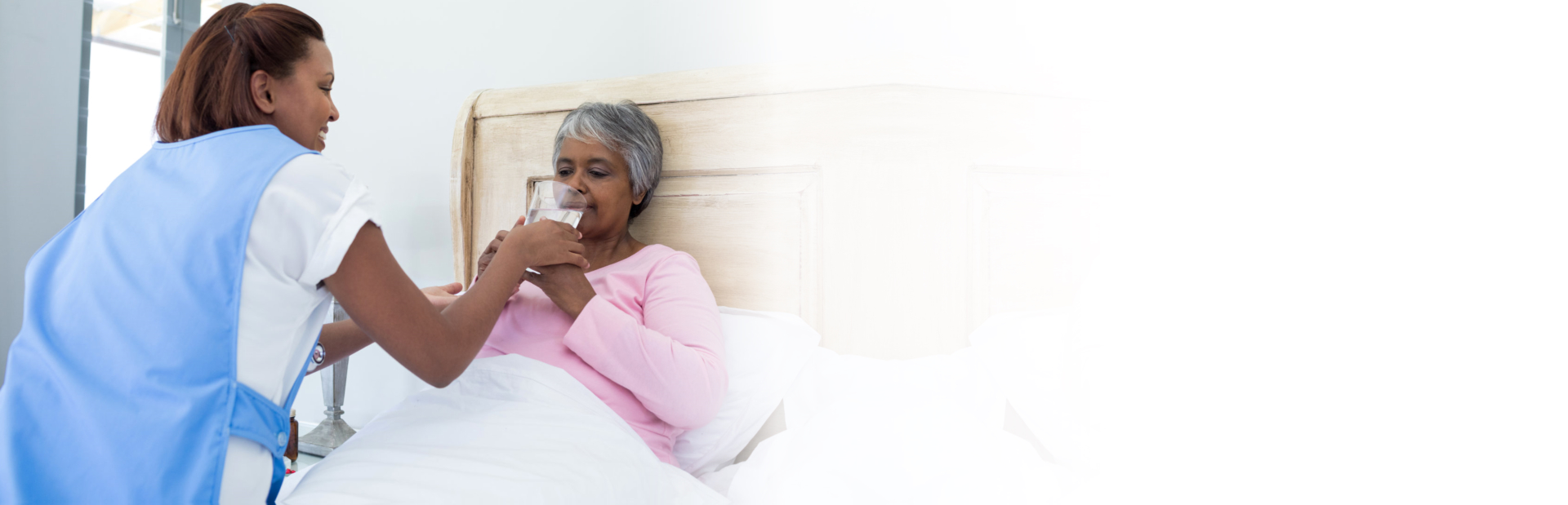 caregiver assisting senior woman drinking water