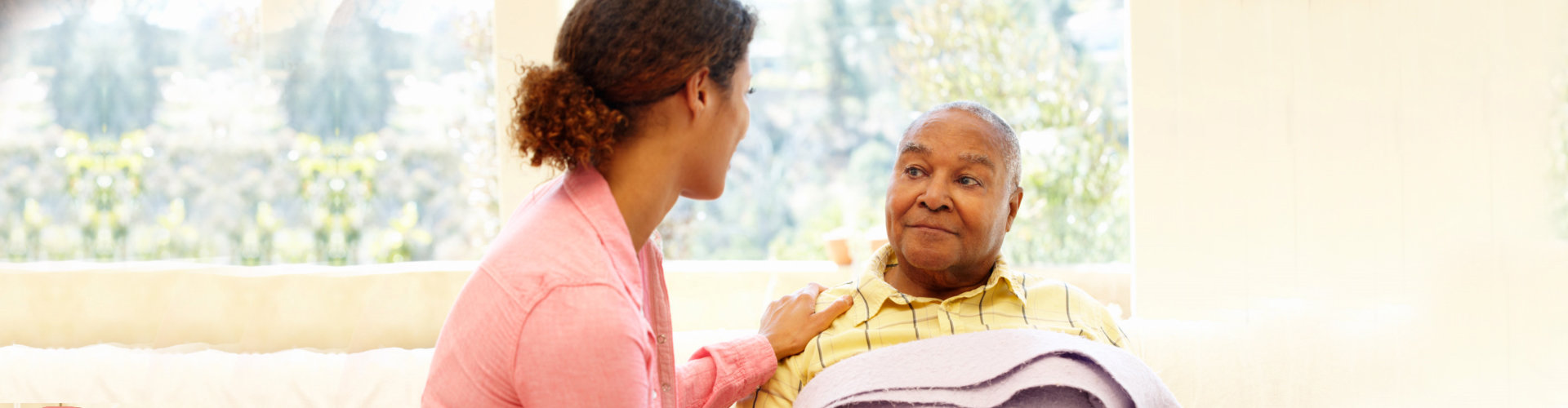 elder man in bed with caregiver beside him